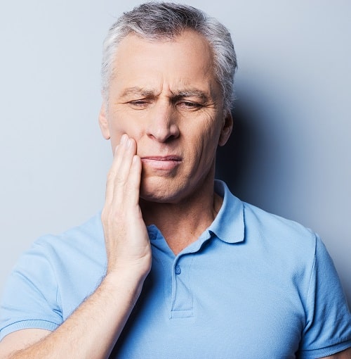 A man holding his painful jaw in need of TMJ treatment from our Prescott experts.