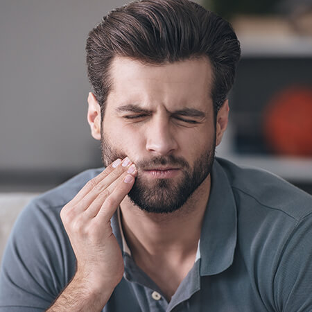 A man holding his jaw because of severe tooth pain